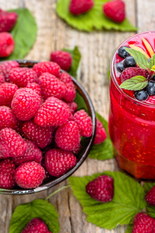 Стакан ягодного смузи на столе со свежими ягодами малины