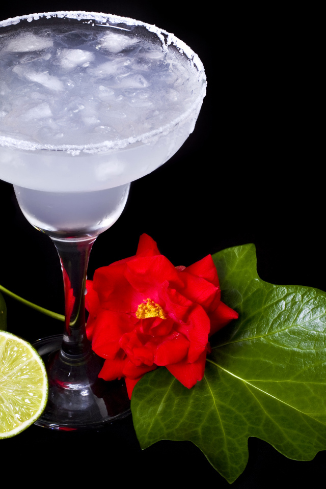 Бокал коктейля со льдом и лаймом на черном фоне