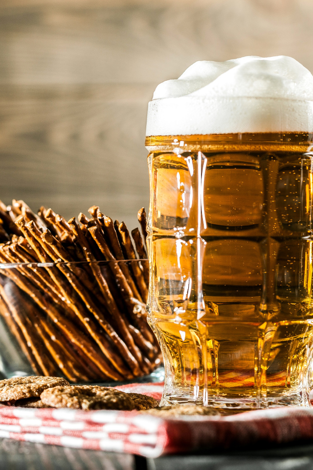 Бокал свежего пива с выпечкой на столе