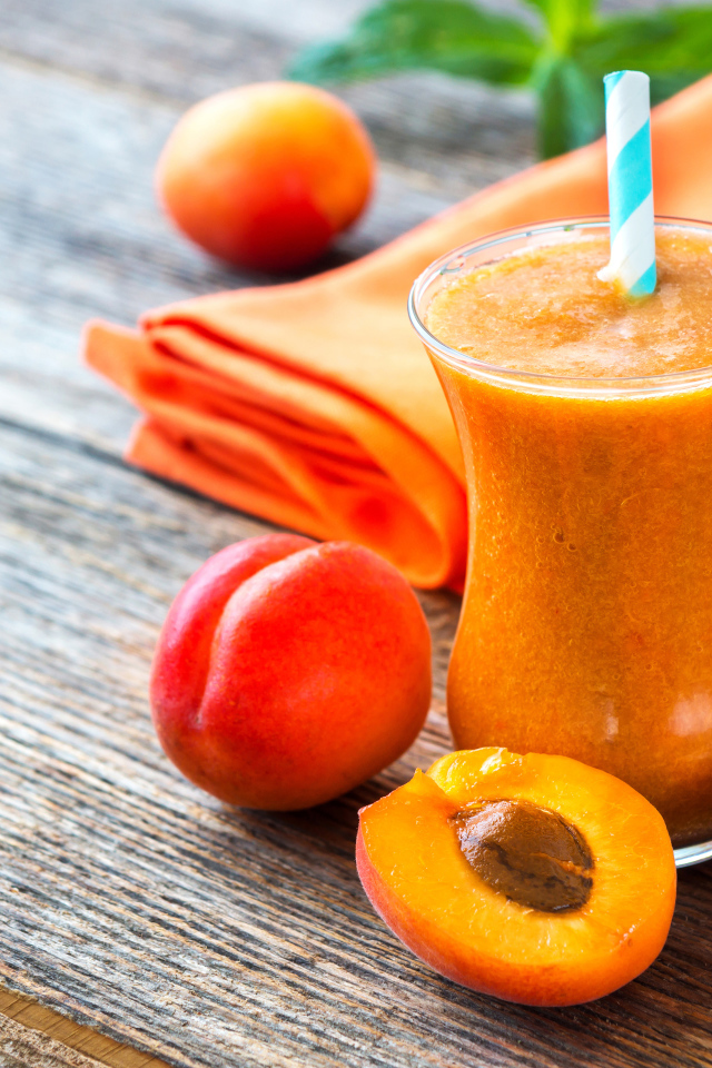 Абрикосовый смузи в стакане на столе со свежими ягодами