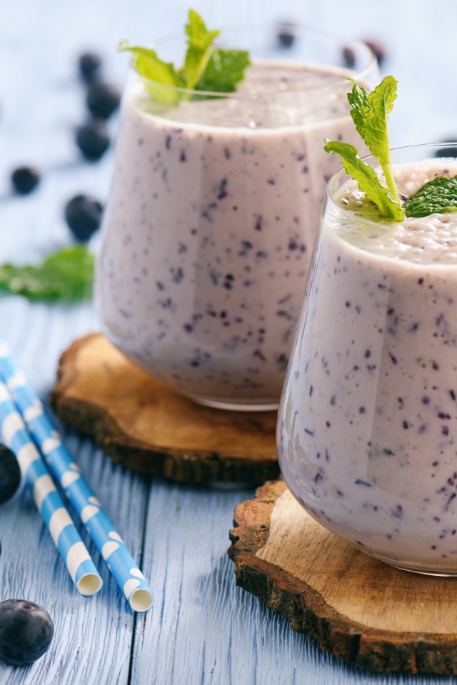 Черничный смузи на столе со свежими ягодами и трубочками