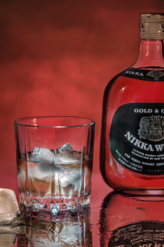 Бутылка Nikka Whisky на столе со стаканом со льдом