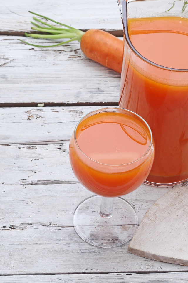 Морковный сок в кувшине на столе с  бокалом