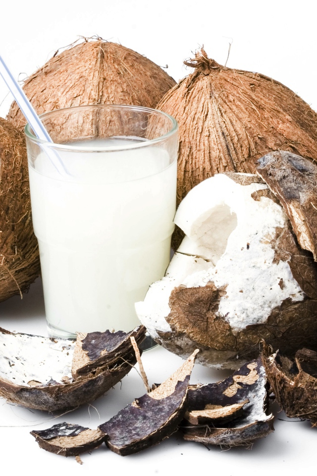 Кокосовое молоко в стакане и кокосы на белом фоне