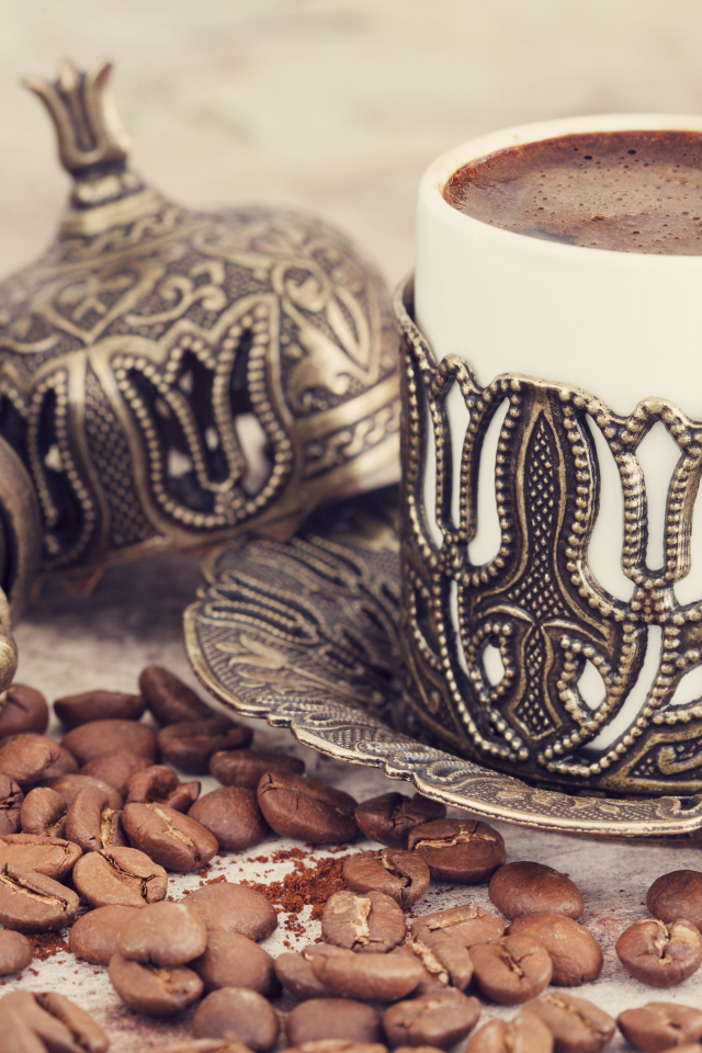 Вкусный кофе в красивой чашке с кофейными зернами на столе