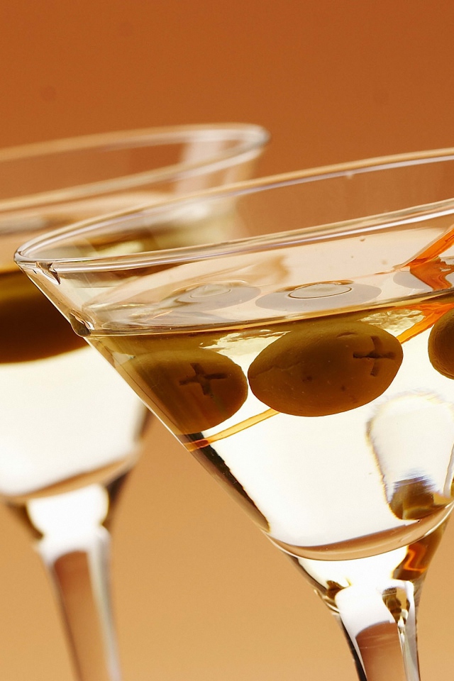 Напиток мартини в бокалах с оливками на кремовом фоне