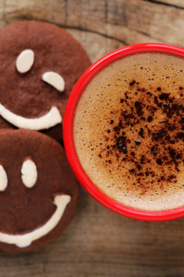 Красная чашка кофе с печеньем смайлами на столе