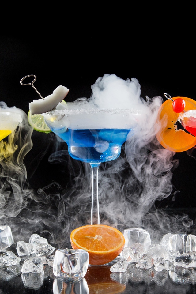 Три алкогольных коктейля с сухим льдом на черном фоне