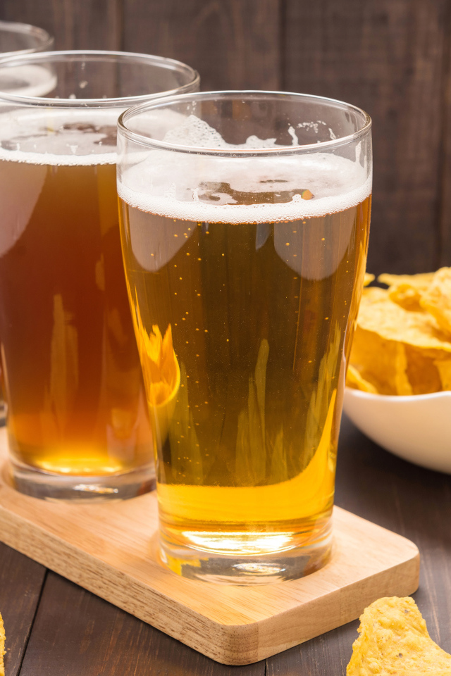 Три стакана пива на столе с чипсами