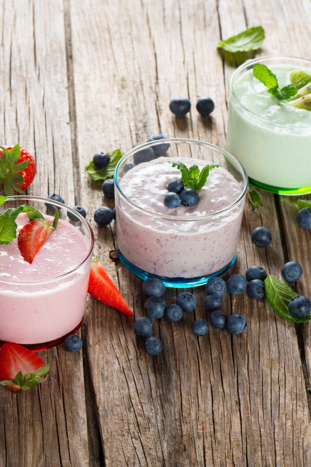 Три стакана смузи с клубникой, киви и черникой и свежими ягодами