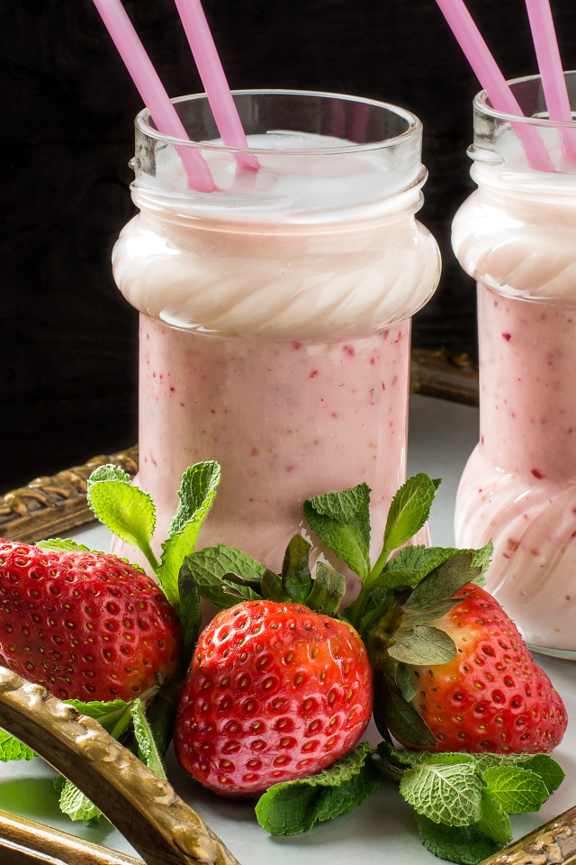 Два свежих клубничных коктейля с трубочками и ягодами клубники