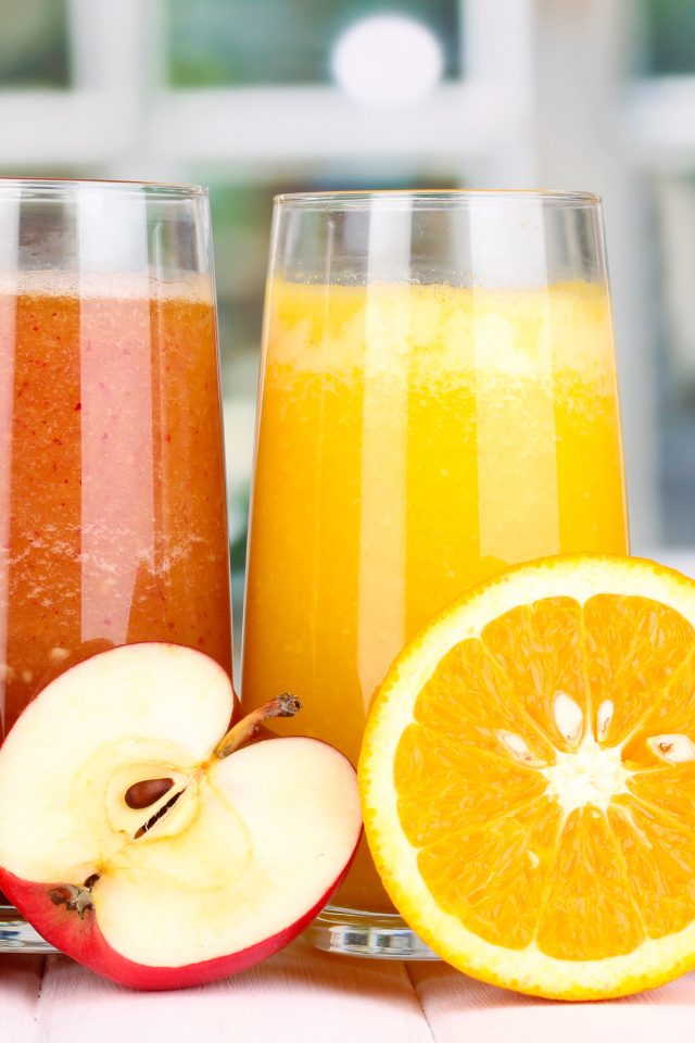 Два стакана с яблочным и апельсиновым соком и свежими фруктами