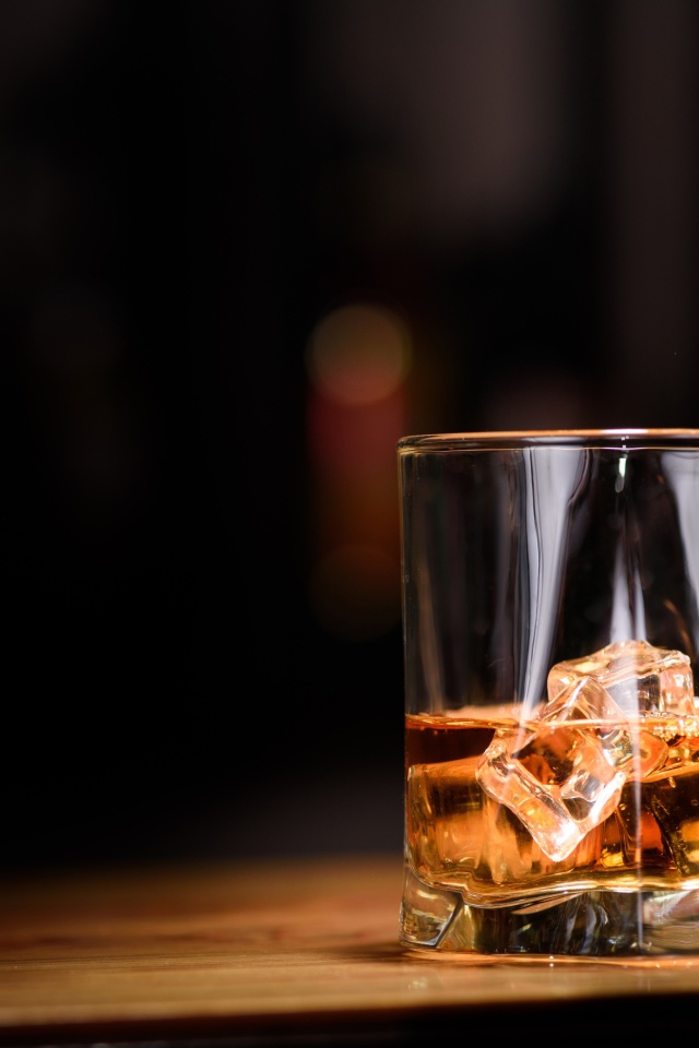 Виски наливают из бутылки в стакан со льдом