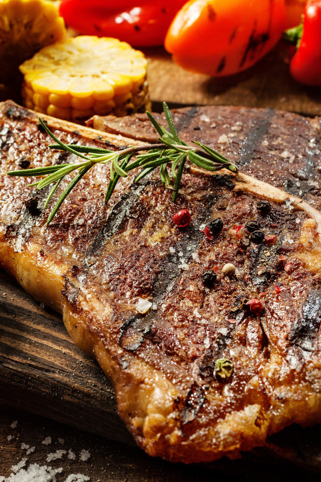 Кусок сочного жареного мяса на разделочной доске с овощами