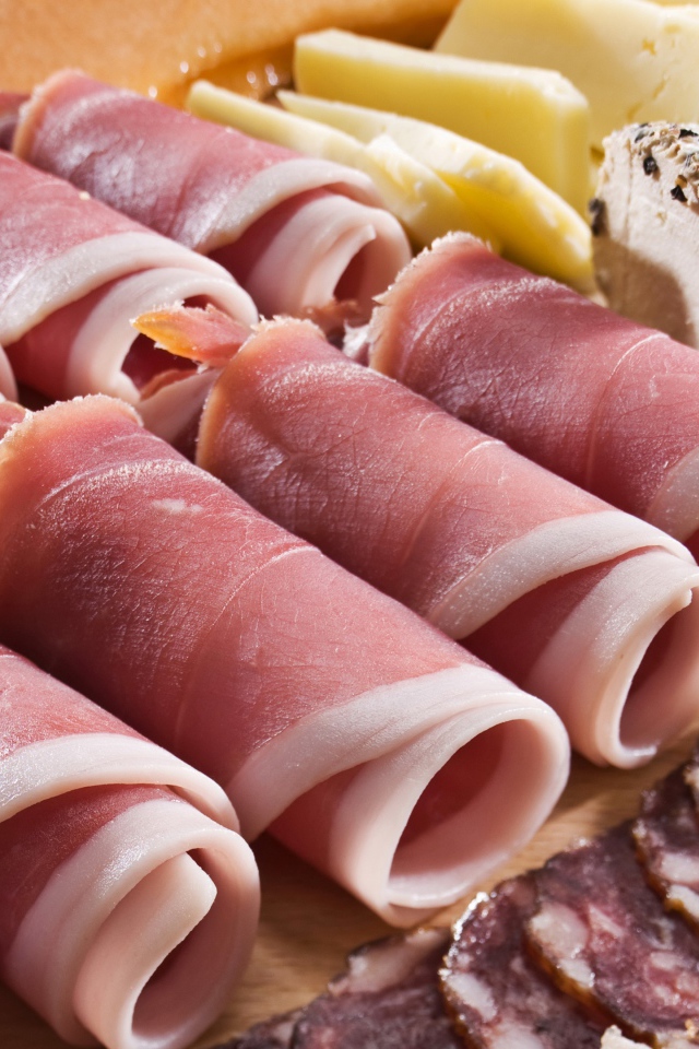 Аппетитные рулетики из бекона на тарелке с зелеными оливками