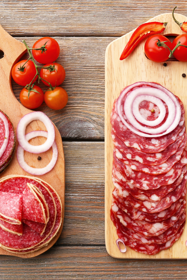 Аппетитная колбасная нарезка на разделочной доске с кольцами лука