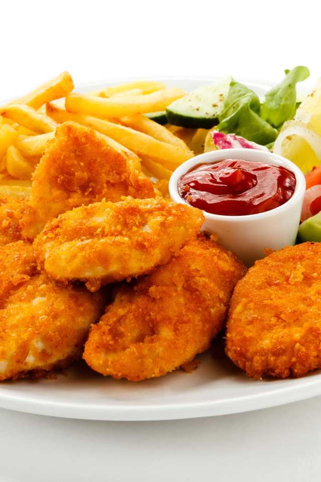 Куриные наггетсы с кетчупом, картофелем фри и салатом на белой тарелке
