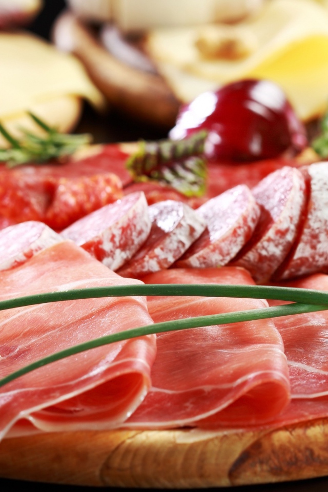 Мясная нарезка на разделочной доске с овощами