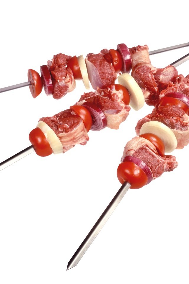 Мясо с овощами для шашлыка на шампурах на белом фоне