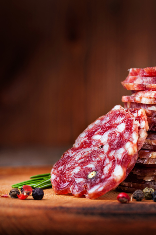 Нарезанная сухая колбаса на столе со специями