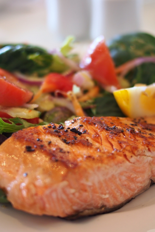 Кусок жареной рыбы с овощами на белой тарелке