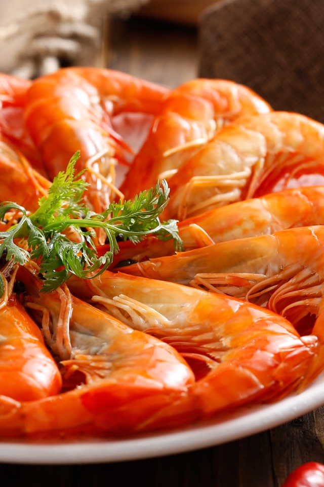 Аппетитные вареные креветки на тарелке с зеленью петрушки