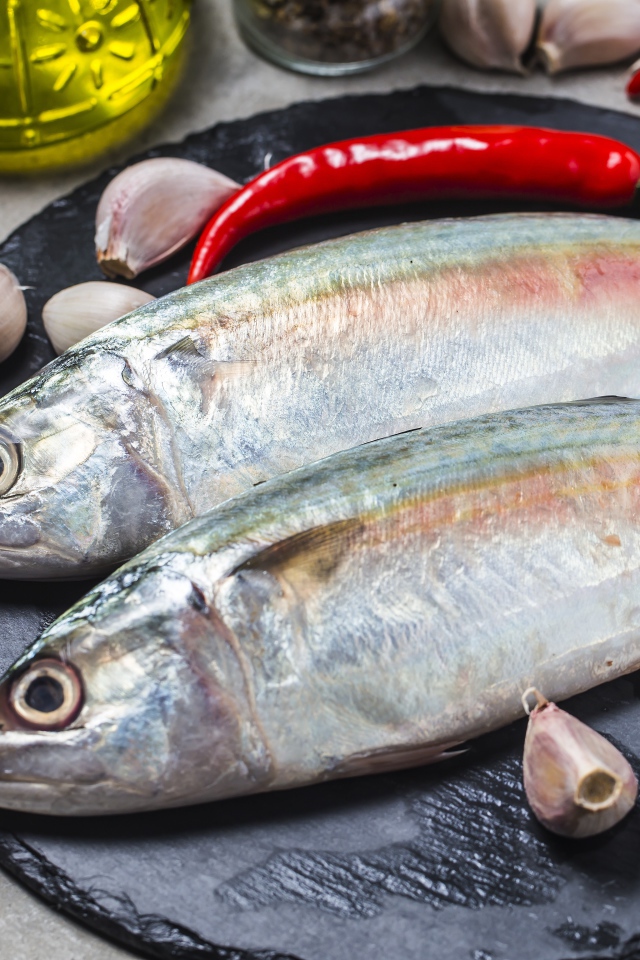 Свежая рыба на столе с красным перцем, чесноком и специями