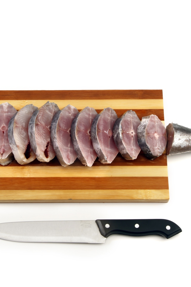 Свежая рыба кусочками на деревянной доске с ножом 