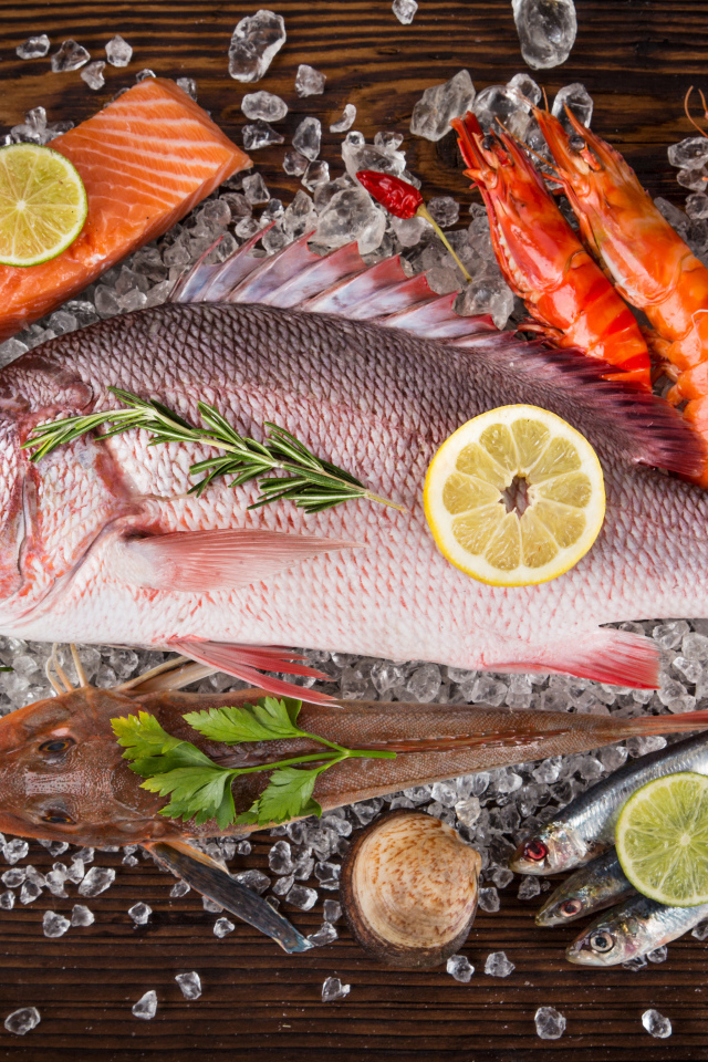 Свежая рыба с креветками и кусочками лимона лежит на кусочках льда