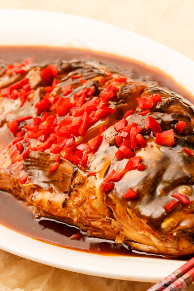 Жареная рыба с соусом и красным перцем в белом блюде