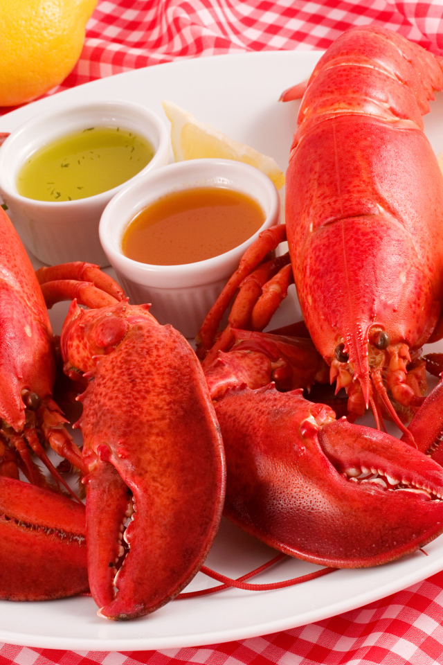 Два вареных омара на тарелке с соусом