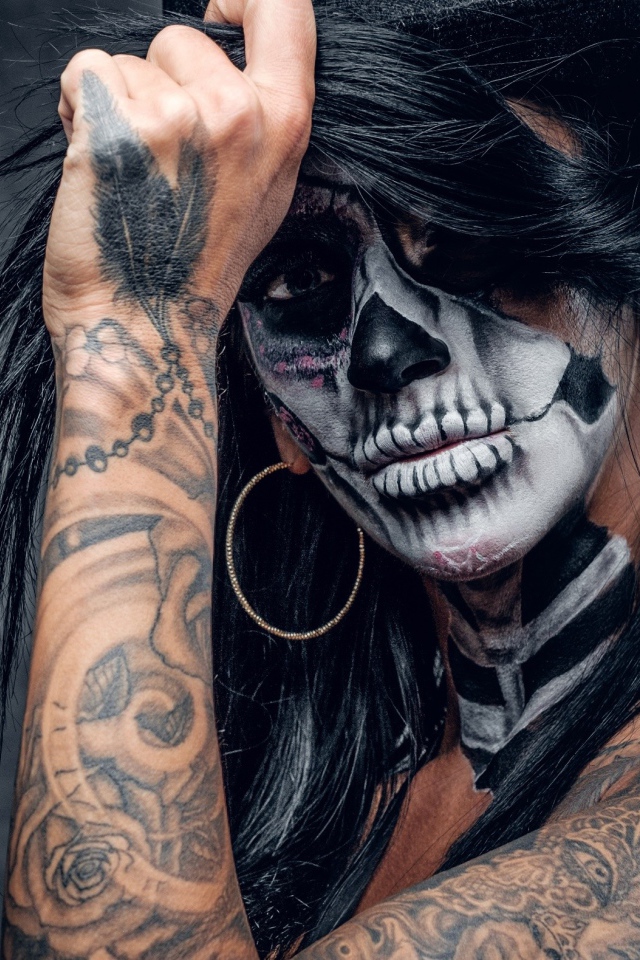 Брюнетка с татуировками и мейкапом на лице 