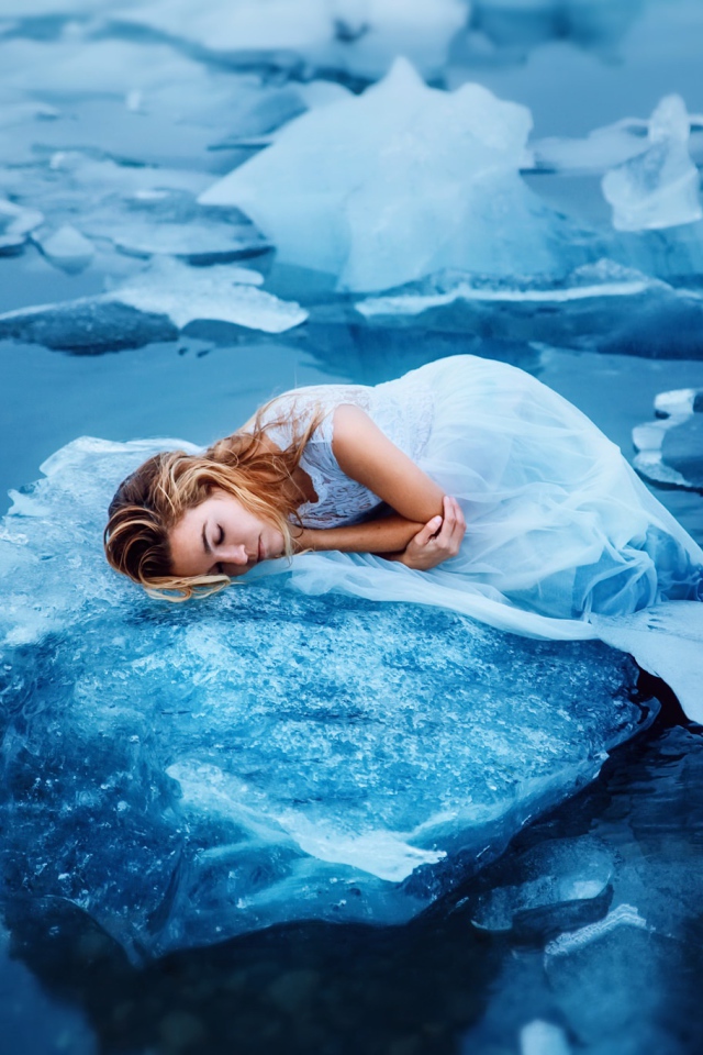 Девушка в красивом белом платье лежит на льдине