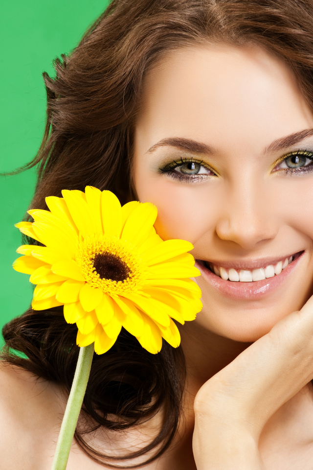 Девушка с красивой улыбкой и цветком желтой герберы в руках