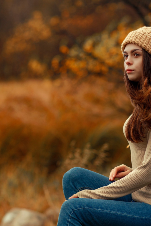 Молодая девушка в синих джинсах и теплой шапке