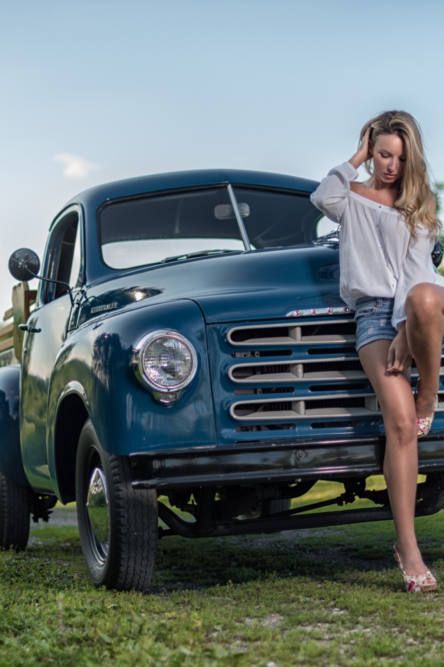 Молодая девушка стоит рядом с зеленым автомобилем Studebaker Pickup, 1953 года