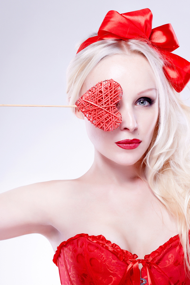 Красивая девушка блондинка в красном наряде с сердечком в руке