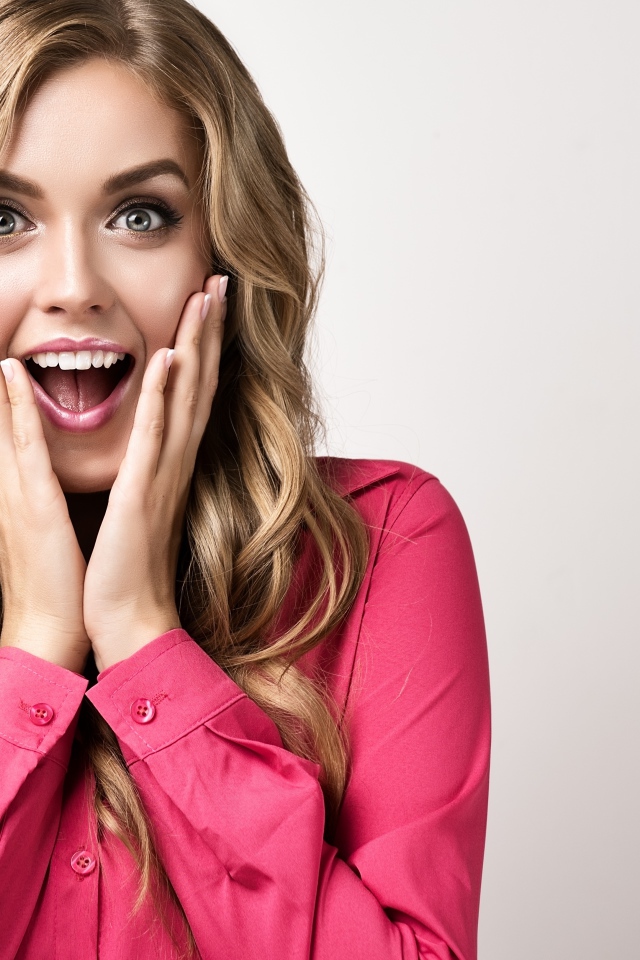 Красивая блондинка в розовой кофте с удивленным лицом