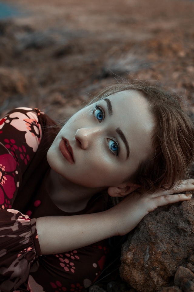 Красивая голубоглазая девушка лежит на камне 