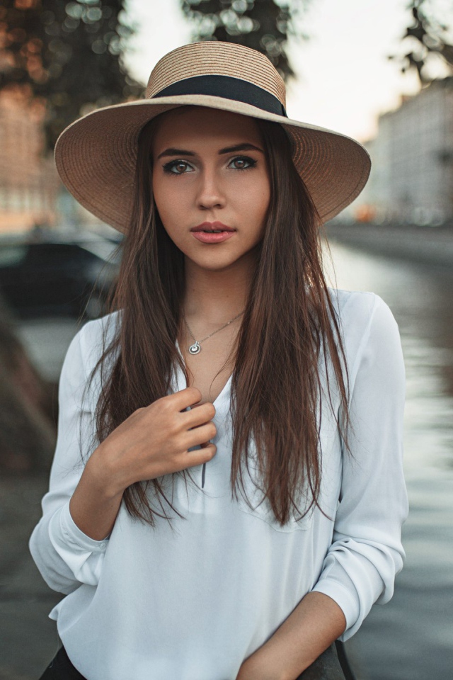 Красивая девушка брюнетка в шляпе у воды