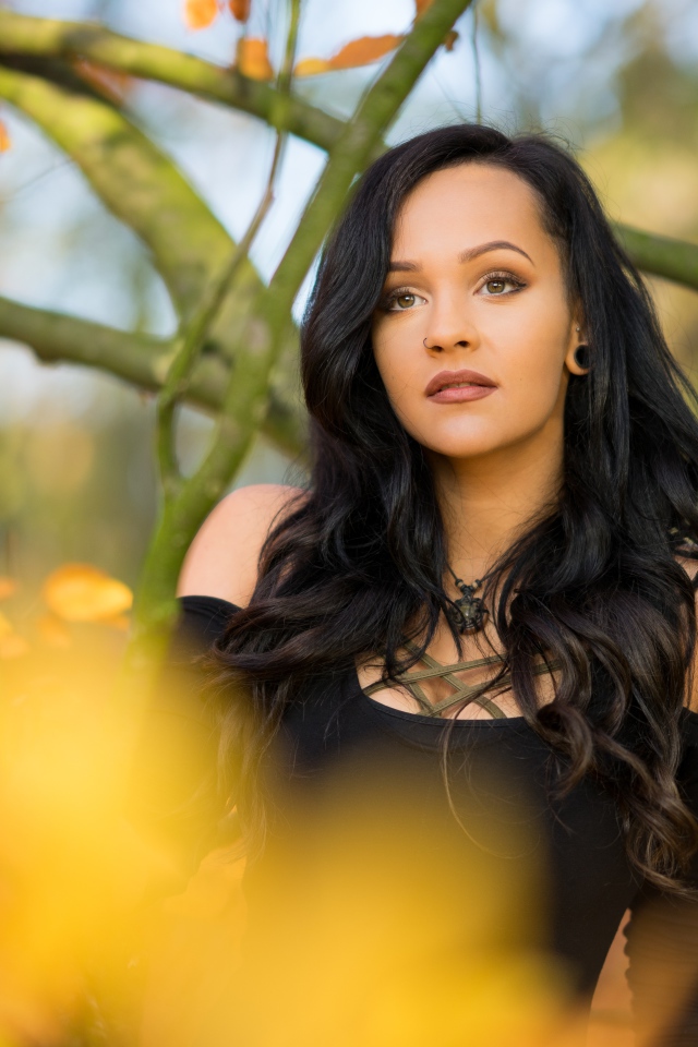 Красивая брюнетка у дерева в черном платье