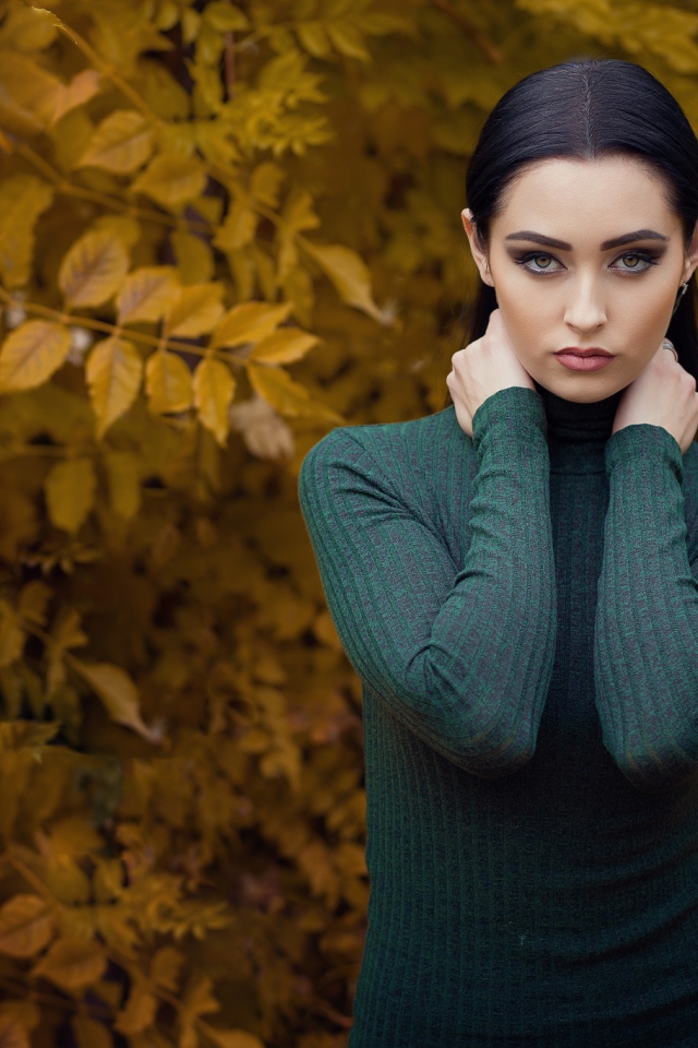 Красивая брюнетка позирует на фоне желтых листьев