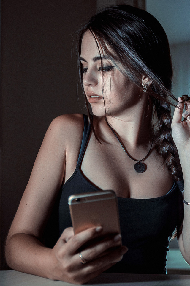 Красивая брюнетка с телефоном в руках и бутылкой