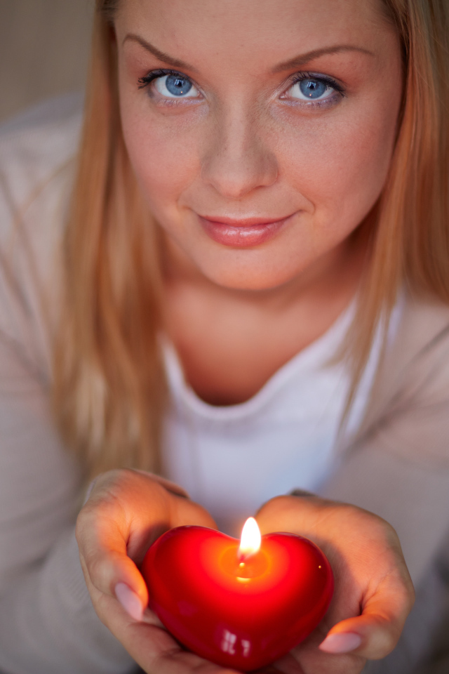 Красивая девушка держит в руках свечу в форме сердца
