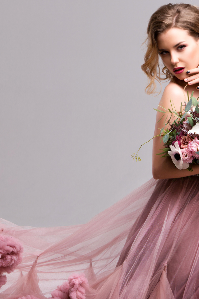 Эффектная девушка в красивом розовом платье с букетом цветов в руках