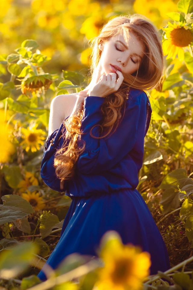 Красивая девушка в голубом платье в поле подсолнухов 