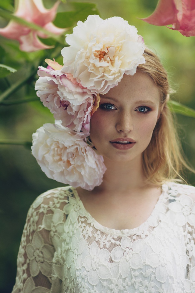Красивая девушка в белом платье с большими пионами в волосах 