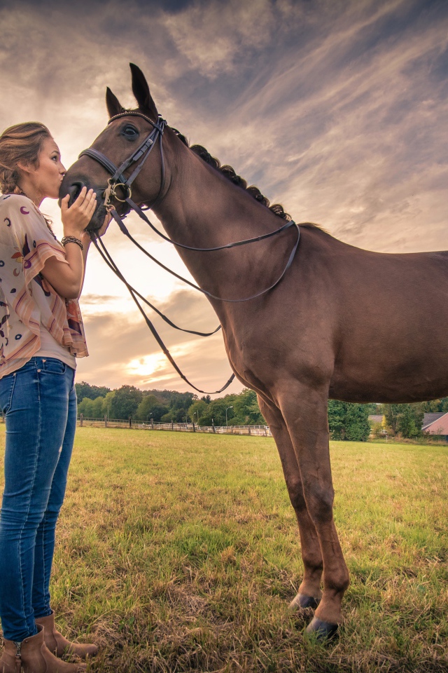 Красивая девушка целует коня под красивым небом