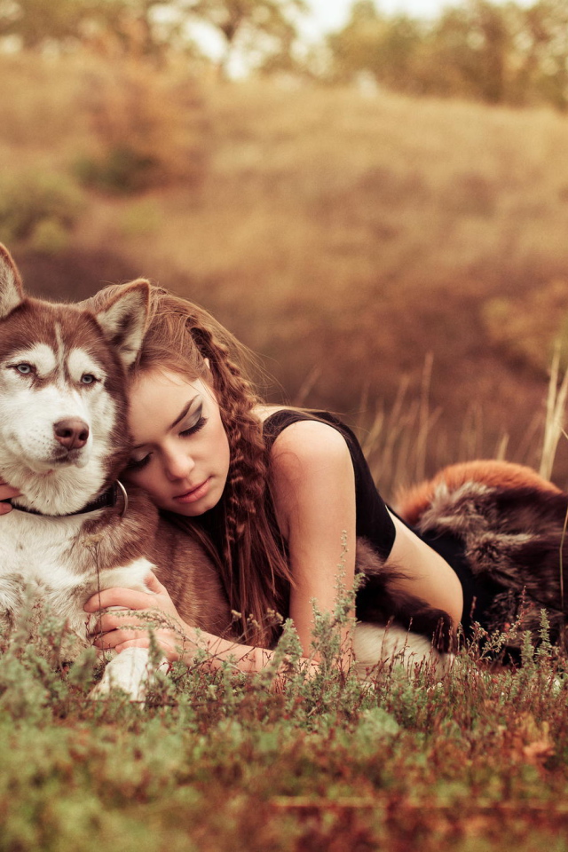 Красивая девушка лежит на траве с собакой породы Хаски