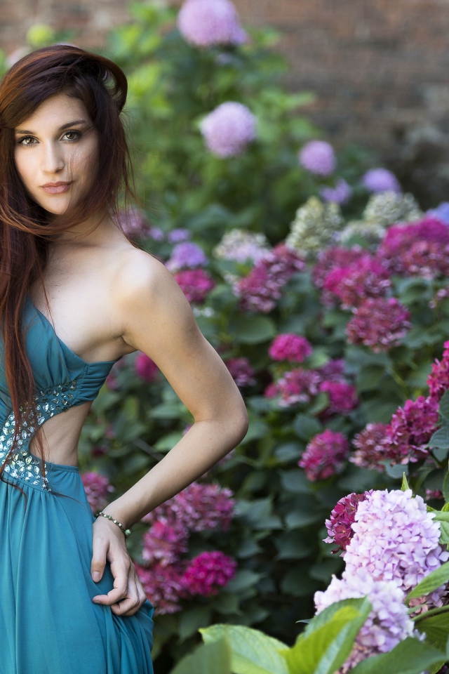 Красивая девушка модель в зеленом платье рядом с цветами гортензии